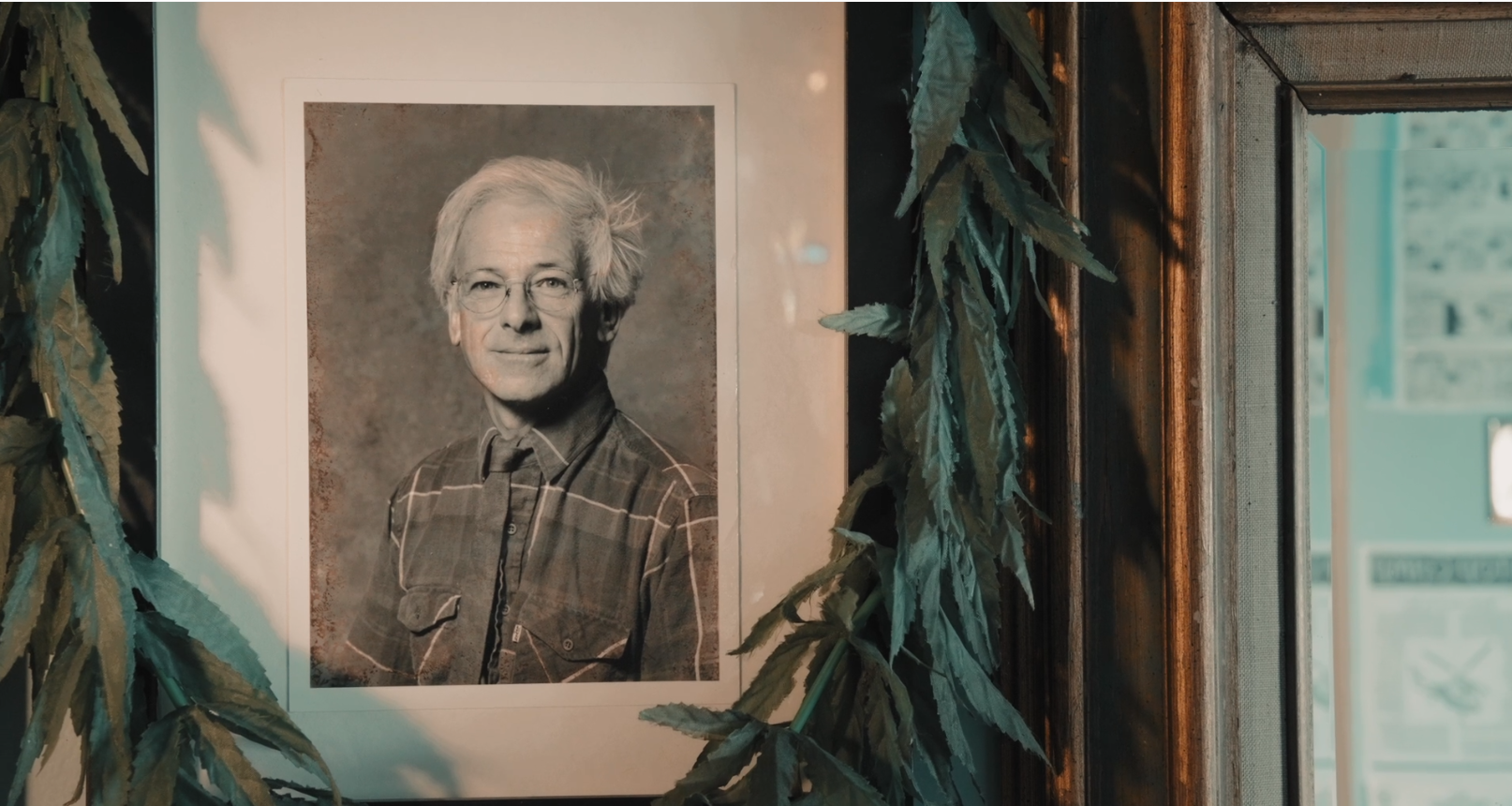 A photo of Dennis Peron surrounded by a string of cannabis leaves is displayed in the San Francisco home he shared with John Entwistle, Jr.